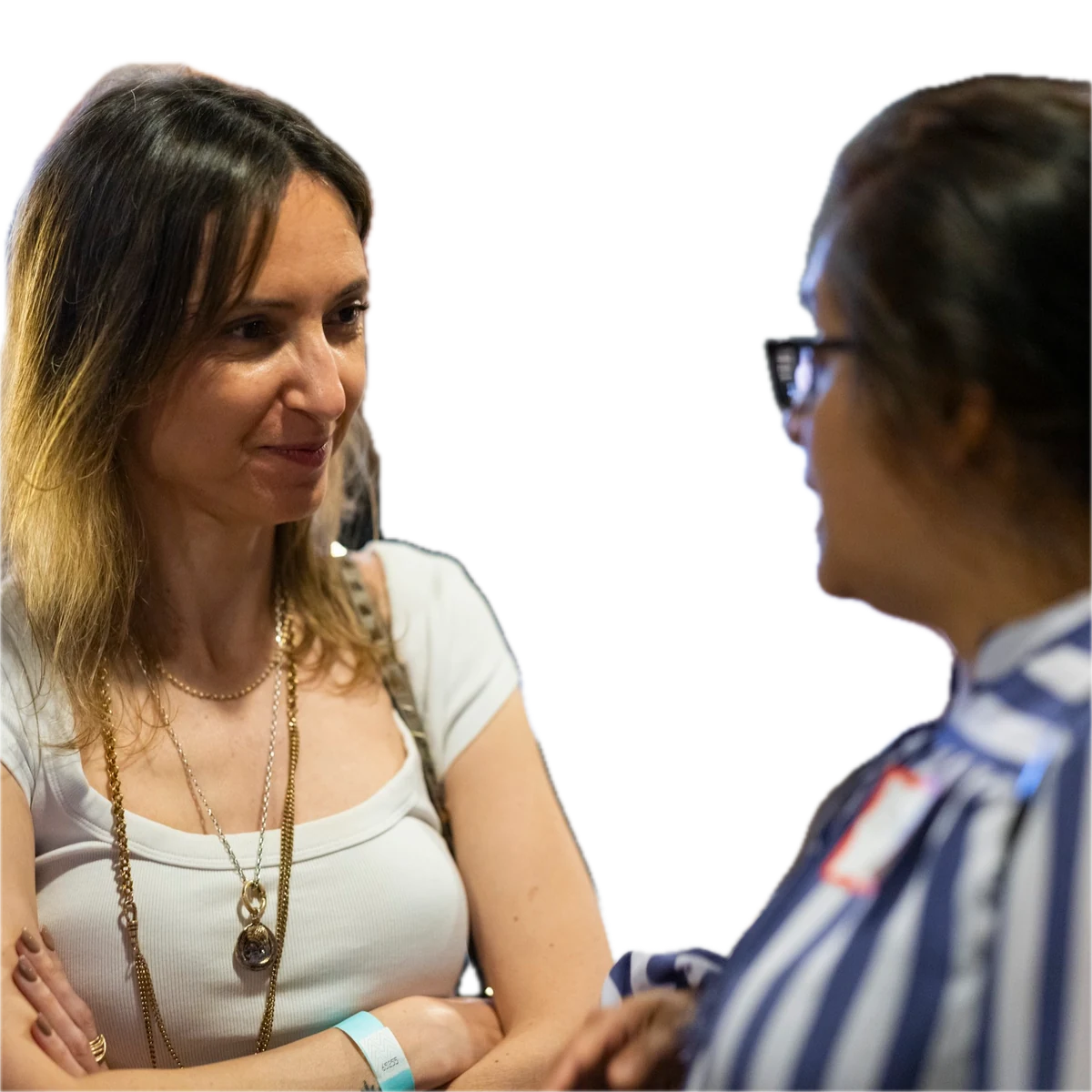 Woman in white tank top smiles during a conversation with another attendee.